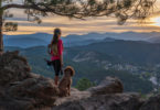 woman is hiking with a dog in the Rocky Mountains