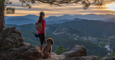 woman is hiking with a dog in the Rocky Mountains